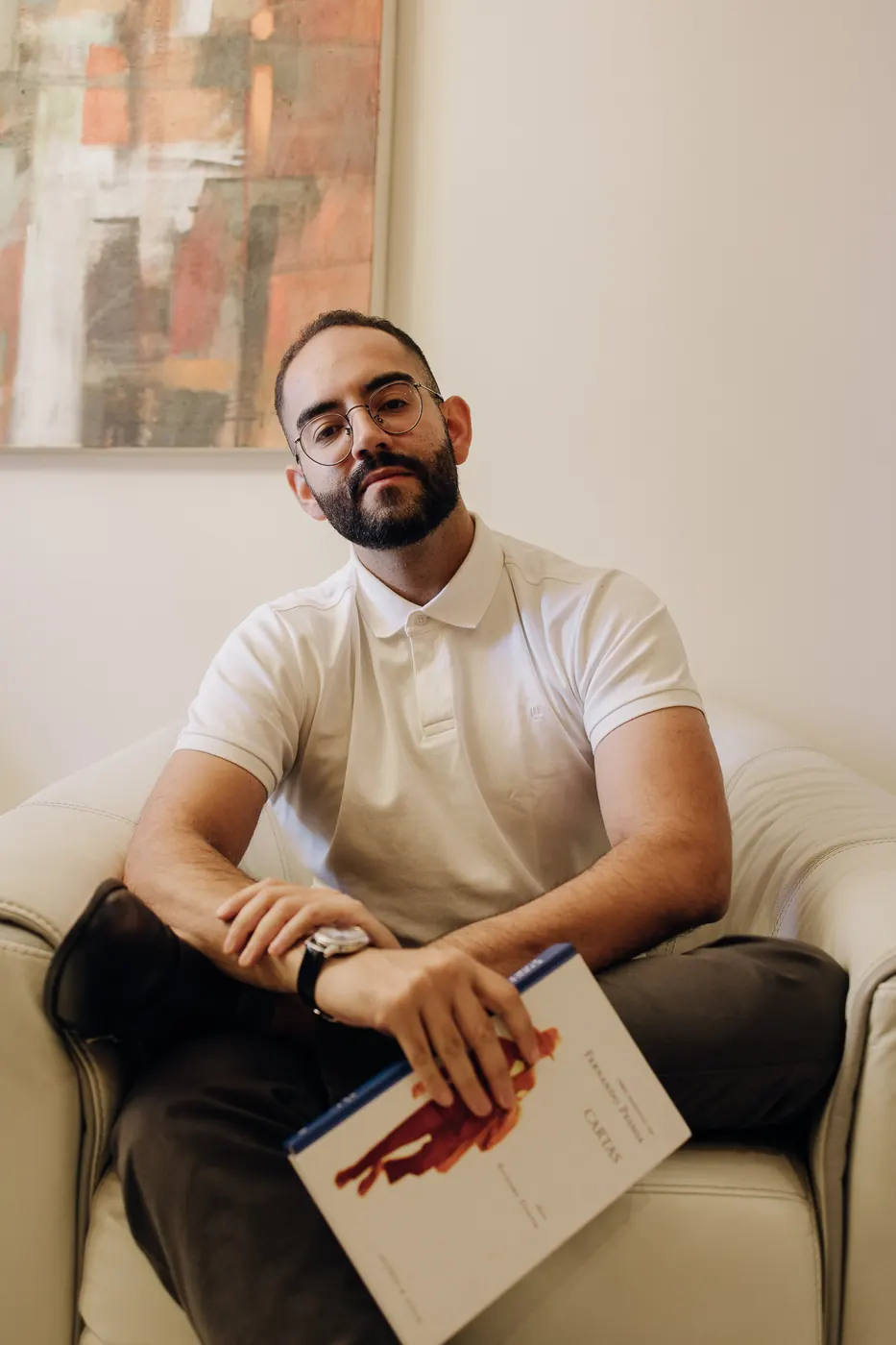 Dr. Ariosto Ribeiro sentado em uma poltrona, com um livro no colo